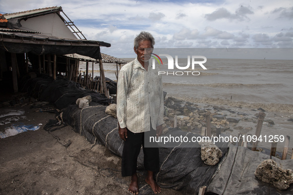 Carmat, 83, is posing for a photo near his house, which was destroyed by high waves in Cemarajaya Village, Karawang Regency, West Java Provi...