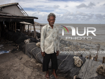 Carmat, 83, is posing for a photo near his house, which was destroyed by high waves in Cemarajaya Village, Karawang Regency, West Java Provi...