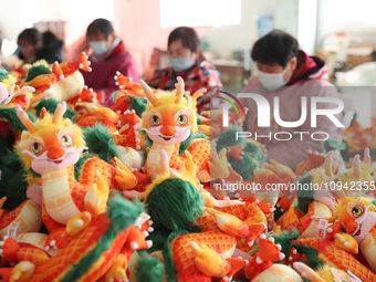 Workers are producing Chinese zodiac dragon toys at a toy company in Chengtou town, Ganyu district, Lianyungang city, Jiangsu province, East...