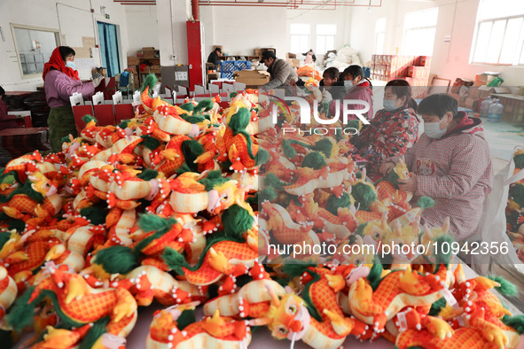 Workers are producing Chinese zodiac dragon toys at a toy company in Chengtou town, Ganyu district, Lianyungang city, Jiangsu province, East...