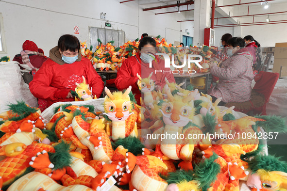 Workers are producing Chinese zodiac dragon toys at a toy company in Chengtou town, Ganyu district, Lianyungang city, Jiangsu province, East...