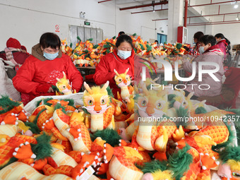 Workers are producing Chinese zodiac dragon toys at a toy company in Chengtou town, Ganyu district, Lianyungang city, Jiangsu province, East...