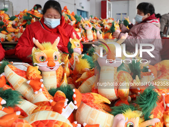 Workers are producing Chinese zodiac dragon toys at a toy company in Chengtou town, Ganyu district, Lianyungang city, Jiangsu province, East...