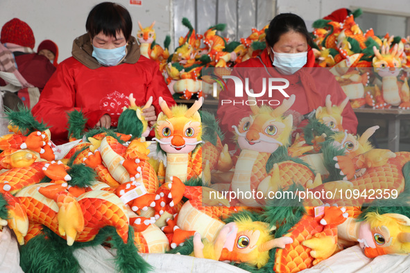 Workers are producing Chinese zodiac dragon toys at a toy company in Chengtou town, Ganyu district, Lianyungang city, Jiangsu province, East...