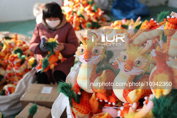 Workers are producing Chinese zodiac dragon toys at a toy company in Chengtou town, Ganyu district, Lianyungang city, Jiangsu province, East...