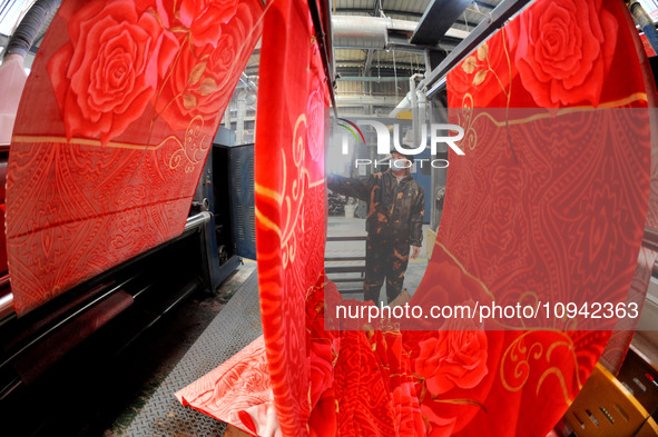 A worker is working on the production line of a warp knitting workshop at Yingyou Blanket Company in Lianyungang, China, on January 27, 2024...