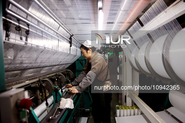 A worker is working on the production line of a warp knitting workshop at Yingyou Blanket Company in Lianyungang, China, on January 27, 2024...