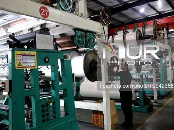 A worker is working on the production line of a warp knitting workshop at Yingyou Blanket Company in Lianyungang, China, on January 27, 2024...