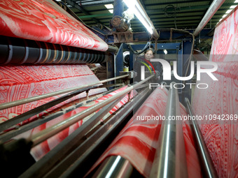 A worker is working on the production line of a warp knitting workshop at Yingyou Blanket Company in Lianyungang, China, on January 27, 2024...