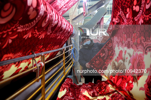 A worker is working on the production line of a warp knitting workshop at Yingyou Blanket Company in Lianyungang, China, on January 27, 2024...