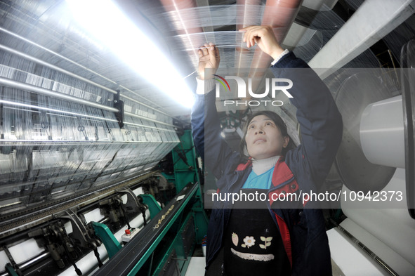 A worker is working on the production line of a warp knitting workshop at Yingyou Blanket Company in Lianyungang, China, on January 27, 2024...