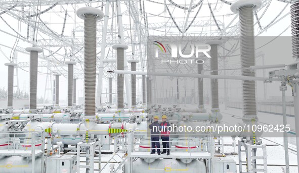 Power workers are carrying out a post-snow inspection of power supply equipment at a 500-kilovolt substation in Meizhuang village, Chuzhou c...