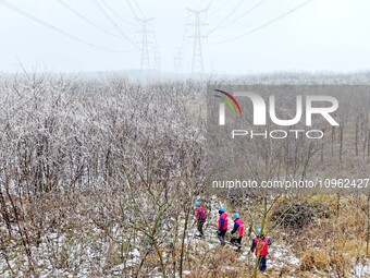 Electric workers are patrolling power supply lines after snow in Meizhou village, Chuzhou, China, on February 4, 2024. (