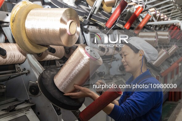 A textile worker is working at a production line of a chemical fiber company in Taizhou, China, on February 10, 2024. 