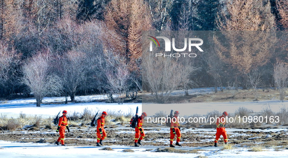 Firefighters are crossing a ditch to patrol forest grassland protection in Zhangye, China, on February 10, 2024. 