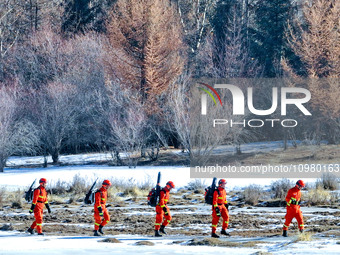 Firefighters are crossing a ditch to patrol forest grassland protection in Zhangye, China, on February 10, 2024. (