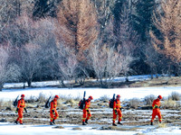 Firefighters are crossing a ditch to patrol forest grassland protection in Zhangye, China, on February 10, 2024. (