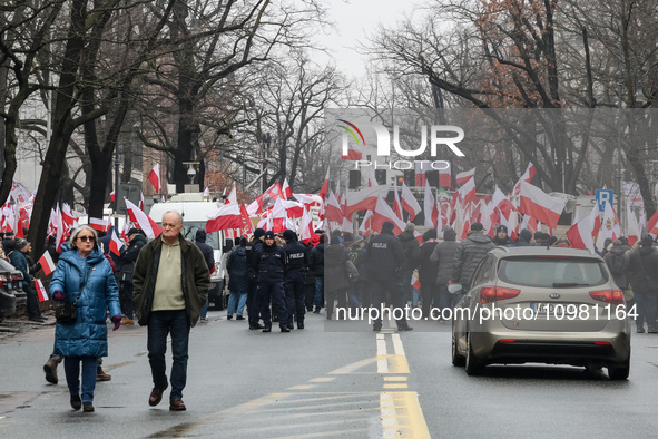 A amall crowd of people, holding Polish national flags and anti-government banners, led by far right media - Gazeta Polska and TV Republica...