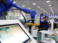 A robot is transferring glass fiber products at the production workshop of a glass fiber company in Chongqing, China, on February 11, 2024....