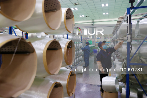 A female worker is inspecting an automated production line at the production workshop of a glass fiber company in Chongqing, China, on Febru...