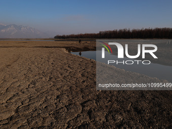 A boy is walking on the dried portion of Wular Lake in the Ningli area of Sopore District, Baramulla, Jammu and Kashmir, India, on February...