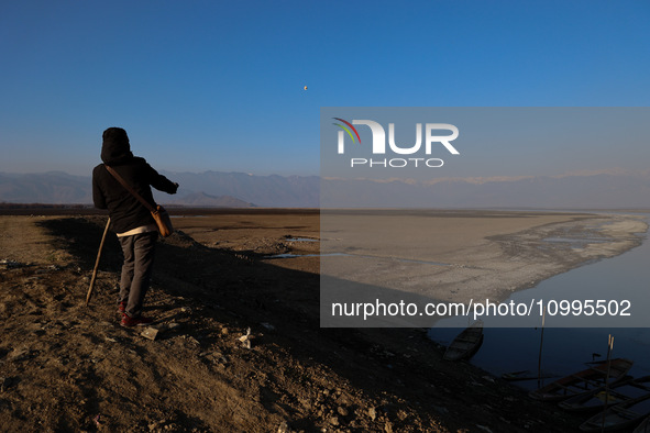 A boy is walking on the dried portion of Wular Lake in the Ningli area of Sopore District, Baramulla, Jammu and Kashmir, India, on February...