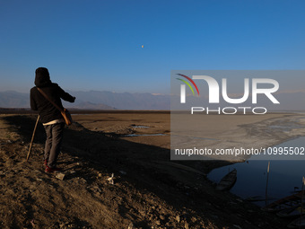 A boy is walking on the dried portion of Wular Lake in the Ningli area of Sopore District, Baramulla, Jammu and Kashmir, India, on February...