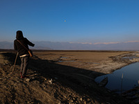 A boy is walking on the dried portion of Wular Lake in the Ningli area of Sopore District, Baramulla, Jammu and Kashmir, India, on February...