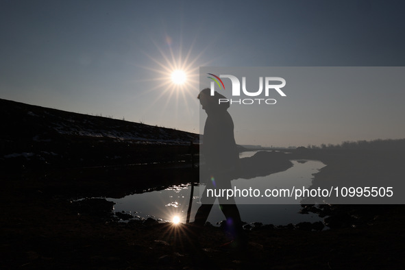 A boy is walking on the dried portion of Wular Lake in the Ningli area of Sopore District, Baramulla, Jammu and Kashmir, India, on February...