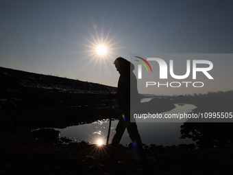 A boy is walking on the dried portion of Wular Lake in the Ningli area of Sopore District, Baramulla, Jammu and Kashmir, India, on February...