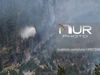 A firefighting helicopter is dropping water to extinguish a wildfire in Port Hills near Christchurch, New Zealand, on February 15, 2024. (