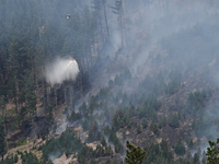 A firefighting helicopter is dropping water to extinguish a wildfire in Port Hills near Christchurch, New Zealand, on February 15, 2024. (