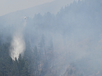 A firefighting helicopter is dropping water to extinguish a wildfire in Port Hills near Christchurch, New Zealand, on February 15, 2024. (