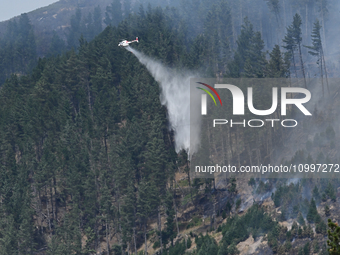 A firefighting helicopter is dropping water to extinguish a wildfire in Port Hills near Christchurch, New Zealand, on February 15, 2024. (