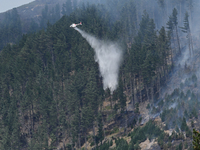 A firefighting helicopter is dropping water to extinguish a wildfire in Port Hills near Christchurch, New Zealand, on February 15, 2024. (