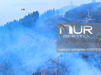 A firefighting helicopter is dropping water to extinguish a wildfire in Port Hills near Christchurch, New Zealand, on February 15, 2024. (