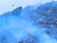 A firefighting helicopter is dropping water to extinguish a wildfire in Port Hills near Christchurch, New Zealand, on February 15, 2024. (