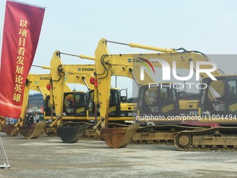 Construction workers are driving an excavator to start construction of the main campus of the Hangzhou Institute for Advanced Studies at the...