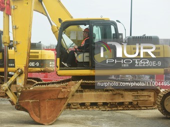 Construction workers are driving an excavator to start construction of the main campus of the Hangzhou Institute for Advanced Studies at the...