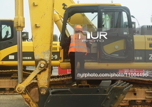 Construction workers are walking into an excavator to start it during the opening ceremony of the main campus of the Hangzhou Institute for...