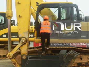 Construction workers are walking into an excavator to start it during the opening ceremony of the main campus of the Hangzhou Institute for...