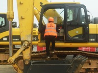 Construction workers are walking into an excavator to start it during the opening ceremony of the main campus of the Hangzhou Institute for...