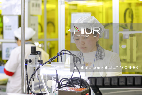 A worker is performing PCB dust removal at a workshop of an automotive electronics company in Qingdao, China, on February 18, 2024. 