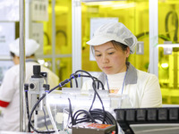 A worker is performing PCB dust removal at a workshop of an automotive electronics company in Qingdao, China, on February 18, 2024. (