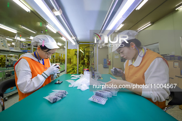 Two workers are carrying out inspection and packaging operations at a workshop of an automotive electronics company in Qingdao, China, on Fe...