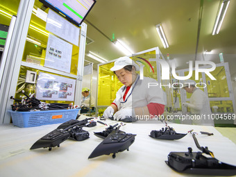 A worker is setting up wiring harnesses in a workshop of an automotive electronics company in Qingdao, China, on February 18, 2024. (