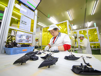 A worker is setting up wiring harnesses in a workshop of an automotive electronics company in Qingdao, China, on February 18, 2024. (