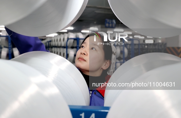 A worker is checking the quality of finished silk at a workshop of a chemical fiber company in Suqian, China, on February 18, 2024. 