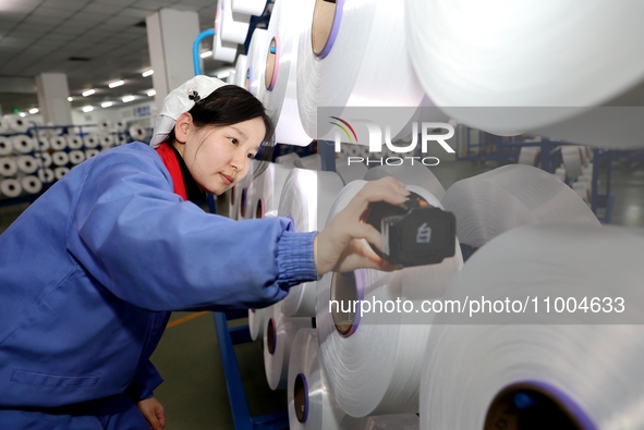 A worker is checking the quality of finished silk at a workshop of a chemical fiber company in Suqian, China, on February 18, 2024. 