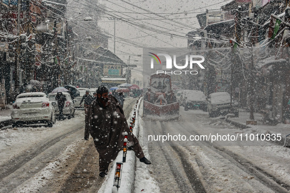 People are walking amid snowfall in Baramulla, Jammu and Kashmir, India, on February 20, 2024. 